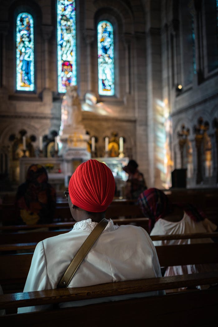 Crafting Captivating Headlines: Your awesome post title goes here A woman prays peacefully in a Paris church with stained glass windows.