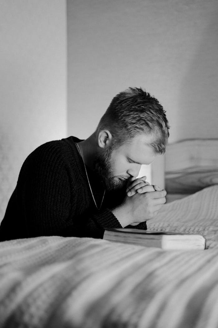 The Art of Drawing Readers In: Your attractive post title goes here A thoughtful man in prayer at home captured in a monochrome portrait.